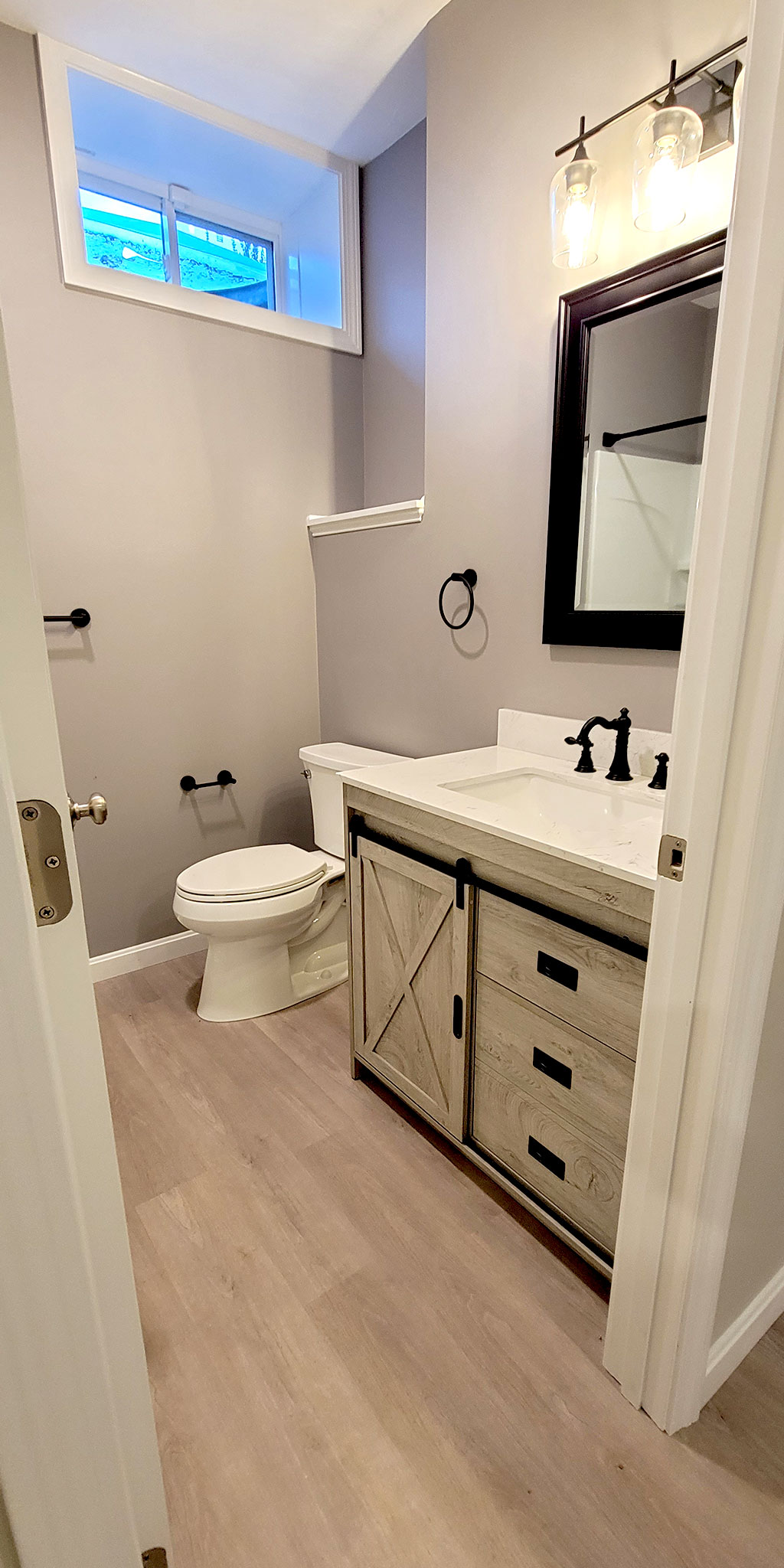 View of part of the new basement bathroom. We had to create a niche with a shelf over the toilet in order to have the existing window entirely inside the bathroom and still have enough room in the adjacent electrical-room. It worked out great and the customer loved it.